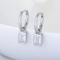 Silver hoop earrings with square gemstones on a white background